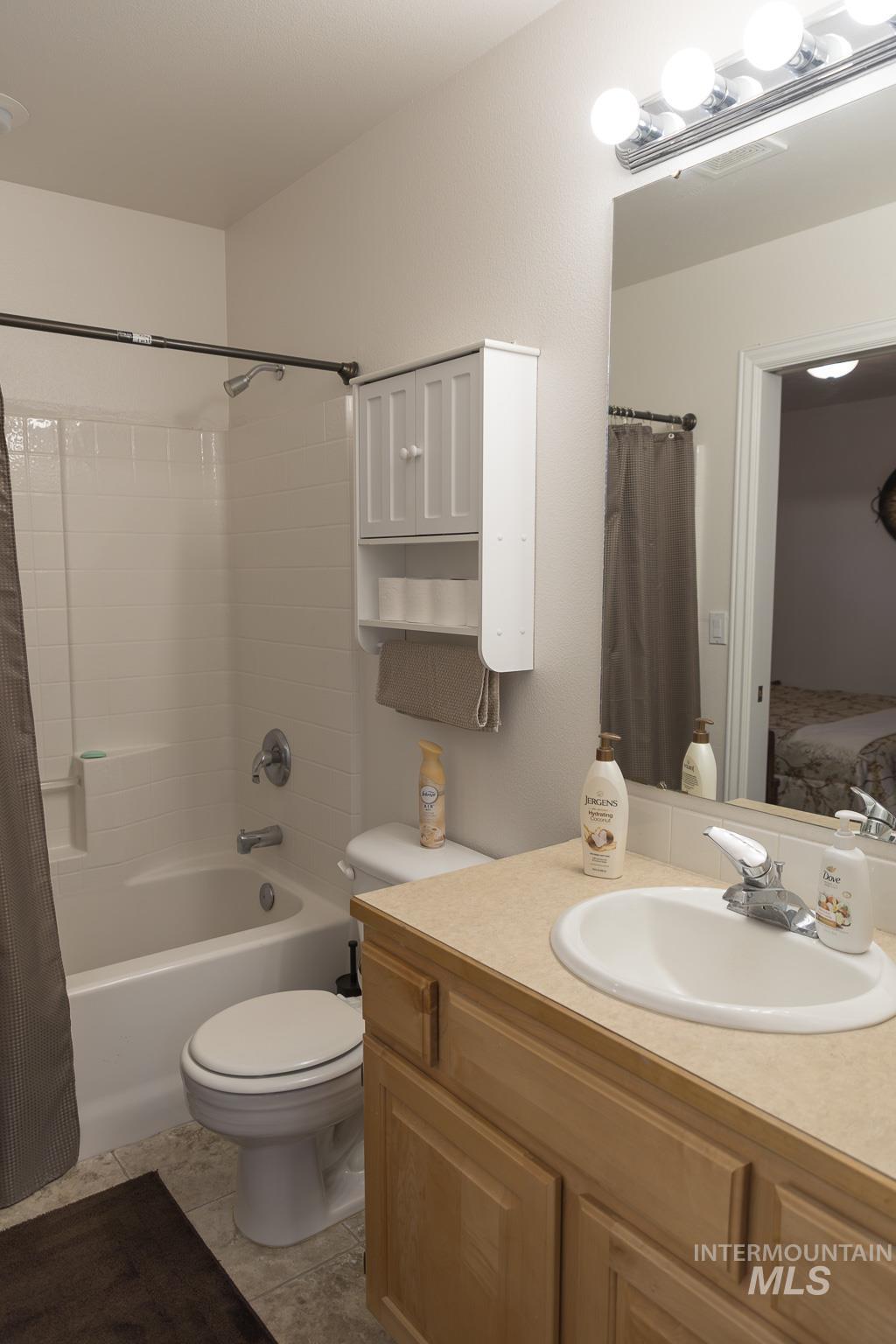 Ensuite bathroom with vanity, shower / tub combo, and light tile patterned floors