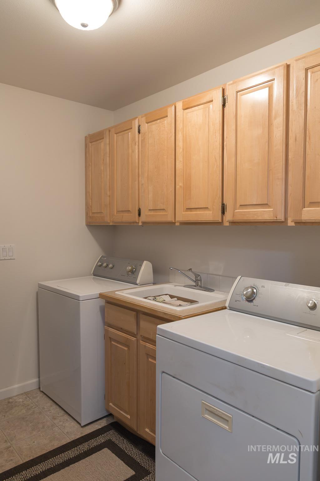 Laundry room featuring cabinet space, light tile patterned flooring, and washer and clothes dryer