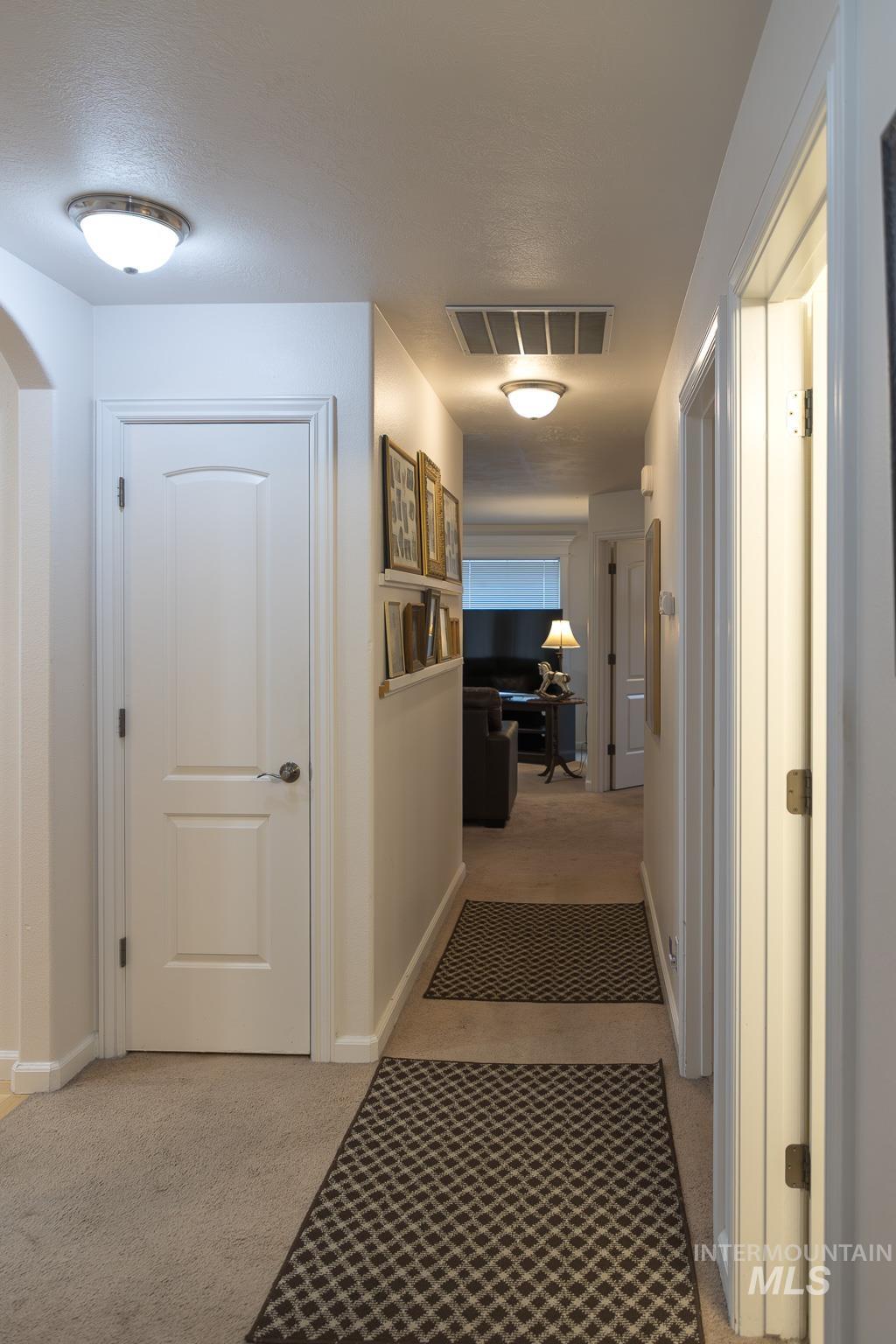 Corridor with light colored carpet and baseboards