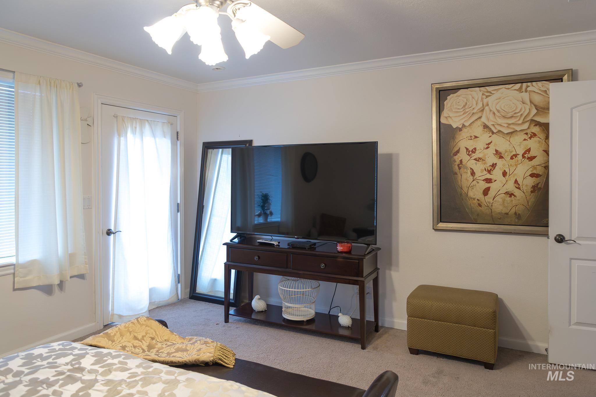 Bedroom with carpet floors, crown molding, and a ceiling fan