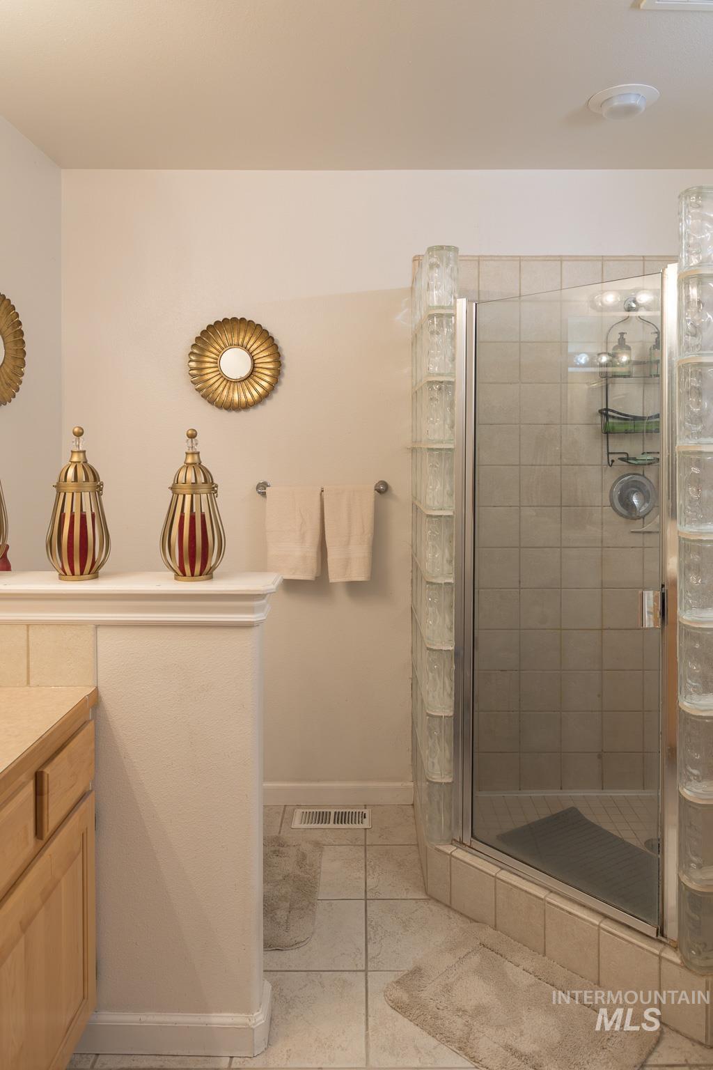 Bathroom with a shower stall, light tile patterned floors, and vanity