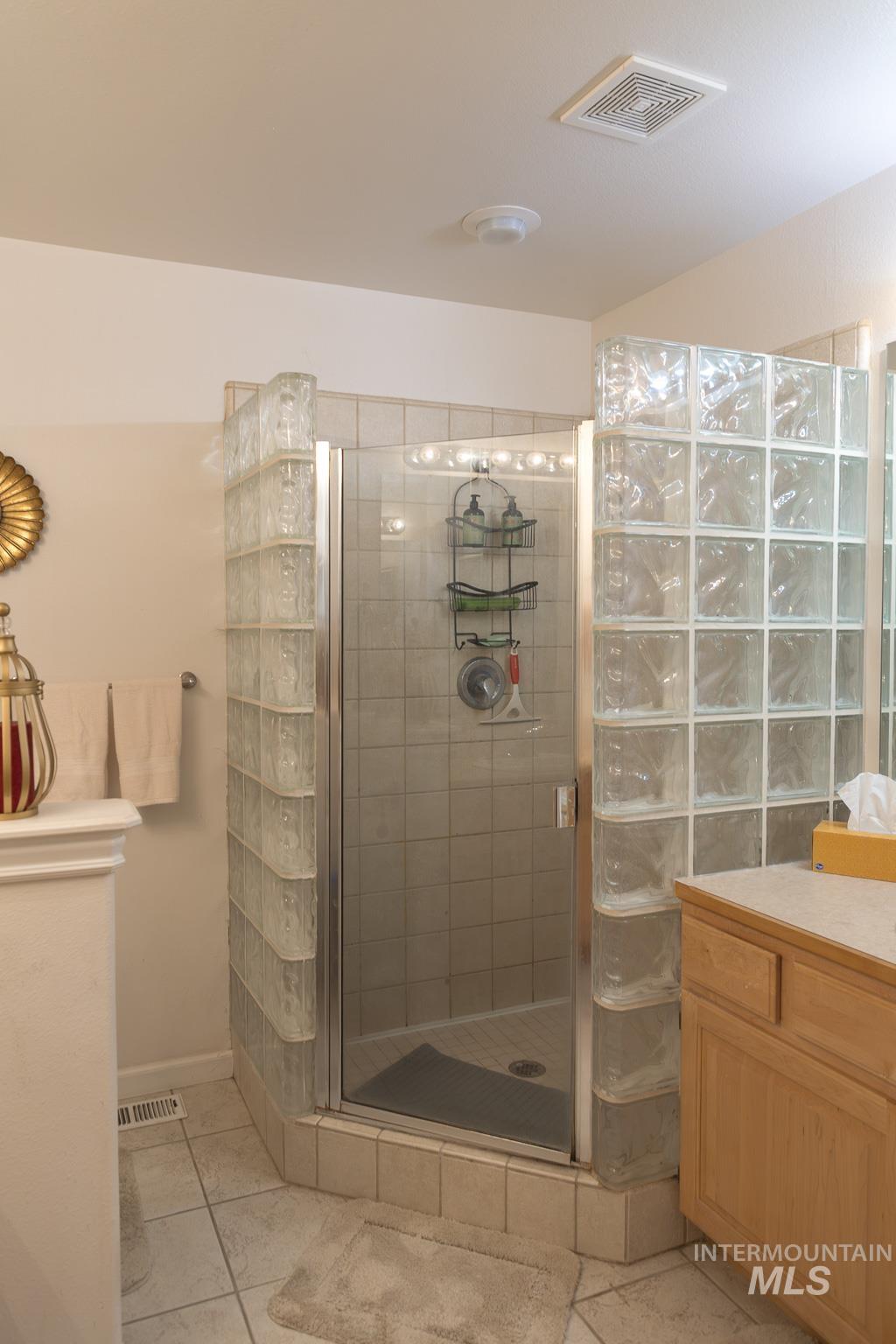 Bathroom with light tile patterned floors, a stall shower, and vanity