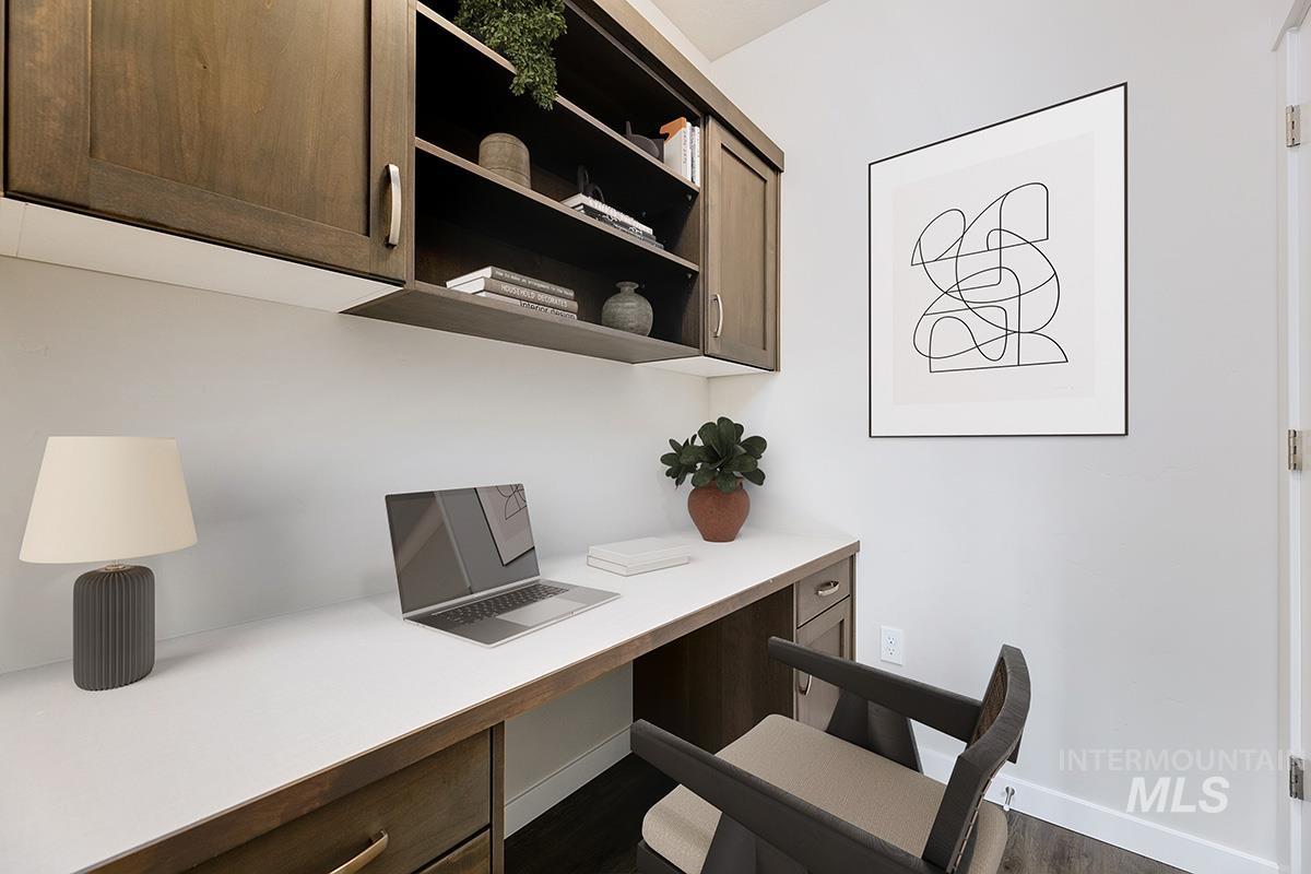 Office area with built in desk and dark wood-type flooring