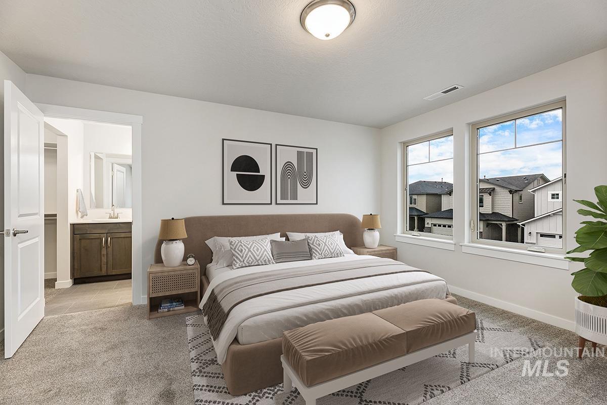 Bedroom featuring light colored carpet and ensuite bath