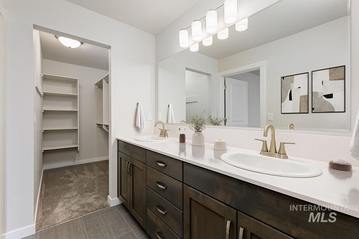 Full bathroom featuring double vanity, dark colored carpet, and a spacious closet