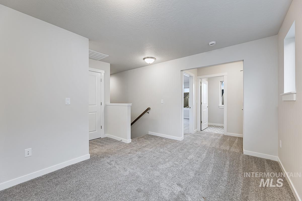 Empty room with a textured ceiling and light colored carpet