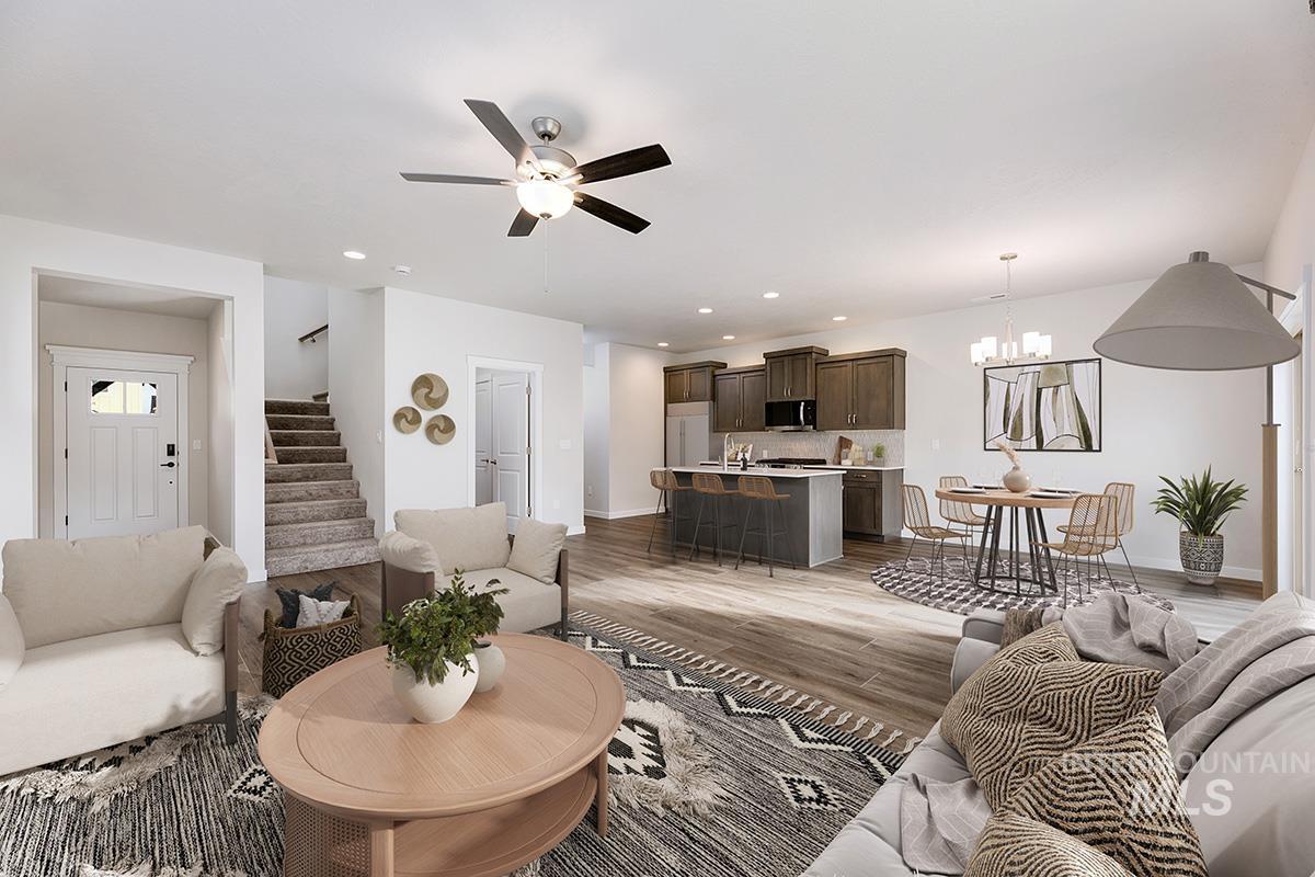 Living room with stairway, a chandelier, ceiling fan, light wood finished floors, and recessed lighting