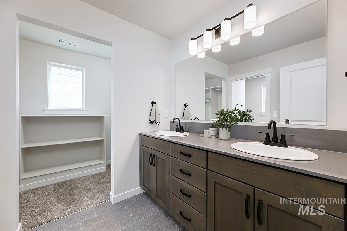 Bathroom featuring double vanity, a spacious closet, and light carpet