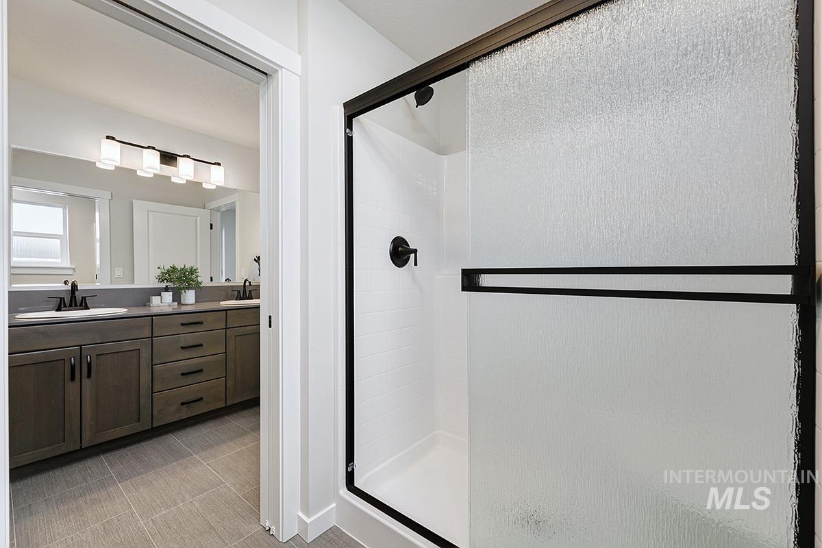 Full bathroom featuring a stall shower and double vanity