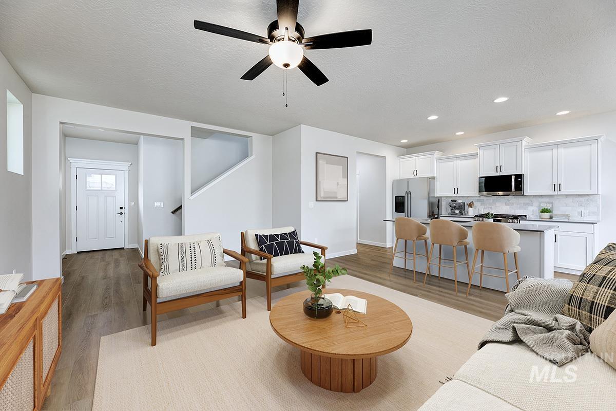 Living room with a textured ceiling, light wood finished floors, ceiling fan, and recessed lighting