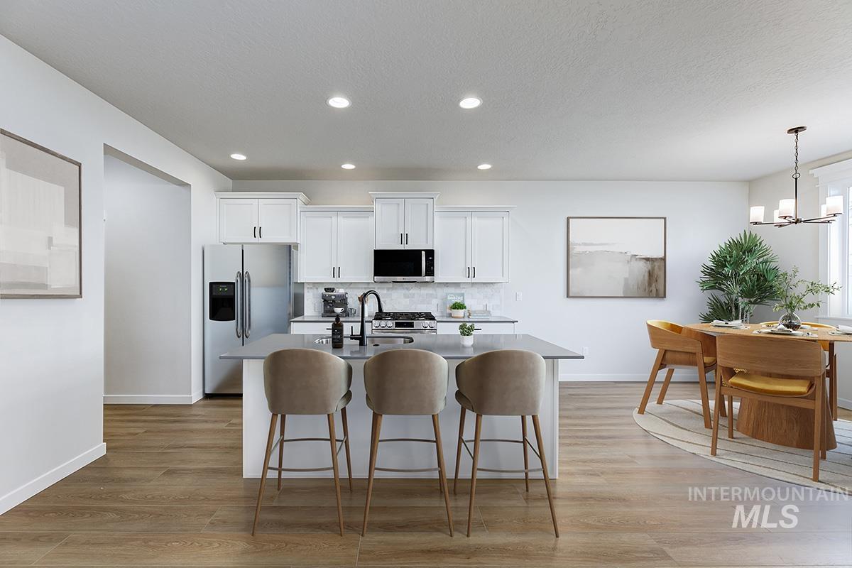 Kitchen with appliances with stainless steel finishes, white cabinetry, a kitchen breakfast bar, light wood finished floors, and recessed lighting