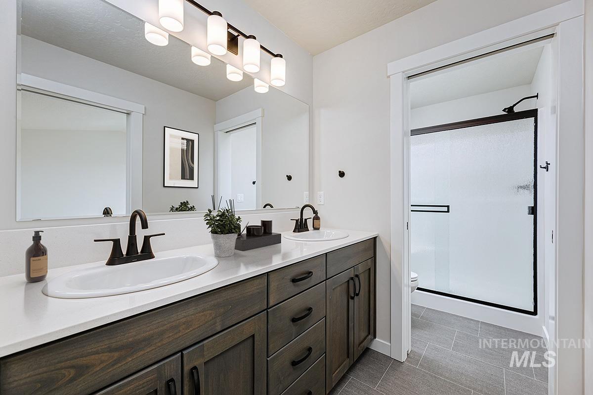 Full bath featuring double vanity, a shower stall, and light tile patterned floors