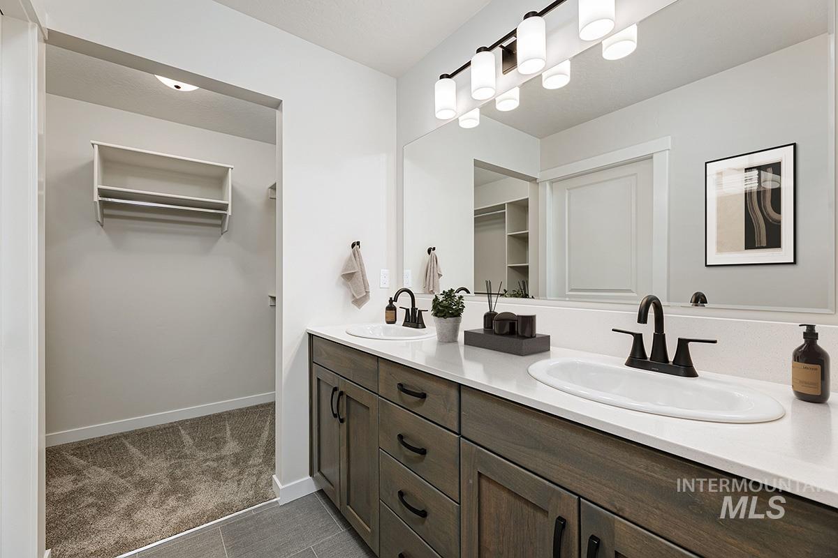 Full bathroom featuring a spacious closet, double vanity, and dark carpet