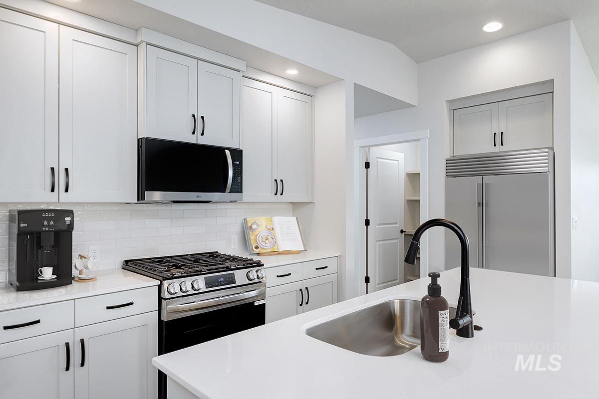 Kitchen with stainless steel appliances, tasteful backsplash, light stone counters, recessed lighting, and white cabinets
