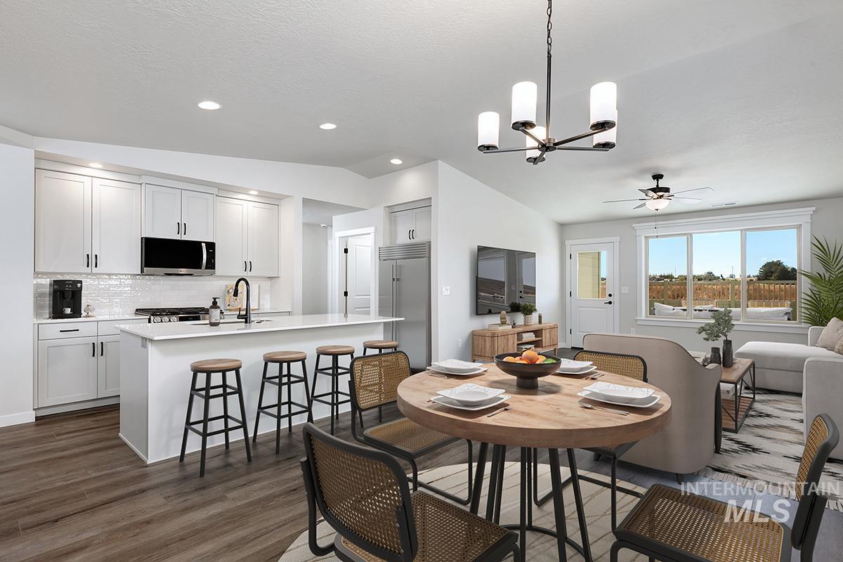 Dining room with vaulted ceiling, a chandelier, dark wood-style flooring, a ceiling fan, and recessed lighting