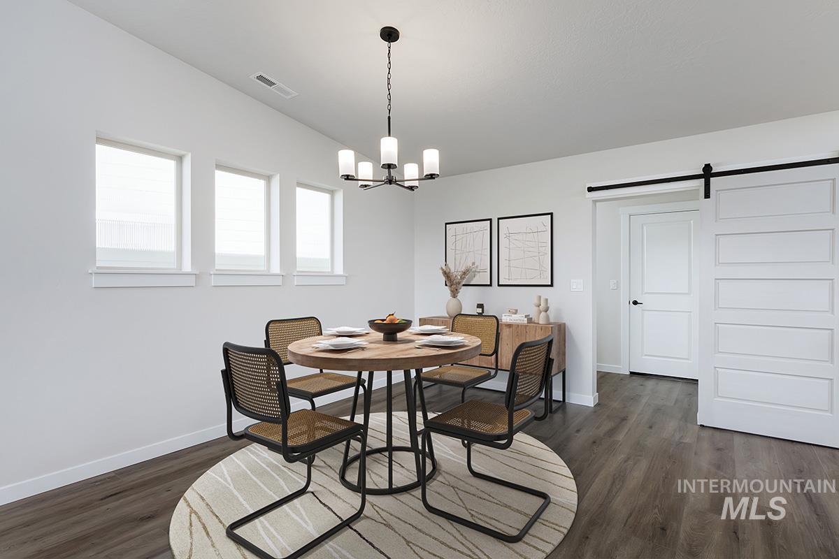 Dining room with a barn door, dark wood finished floors, and a chandelier