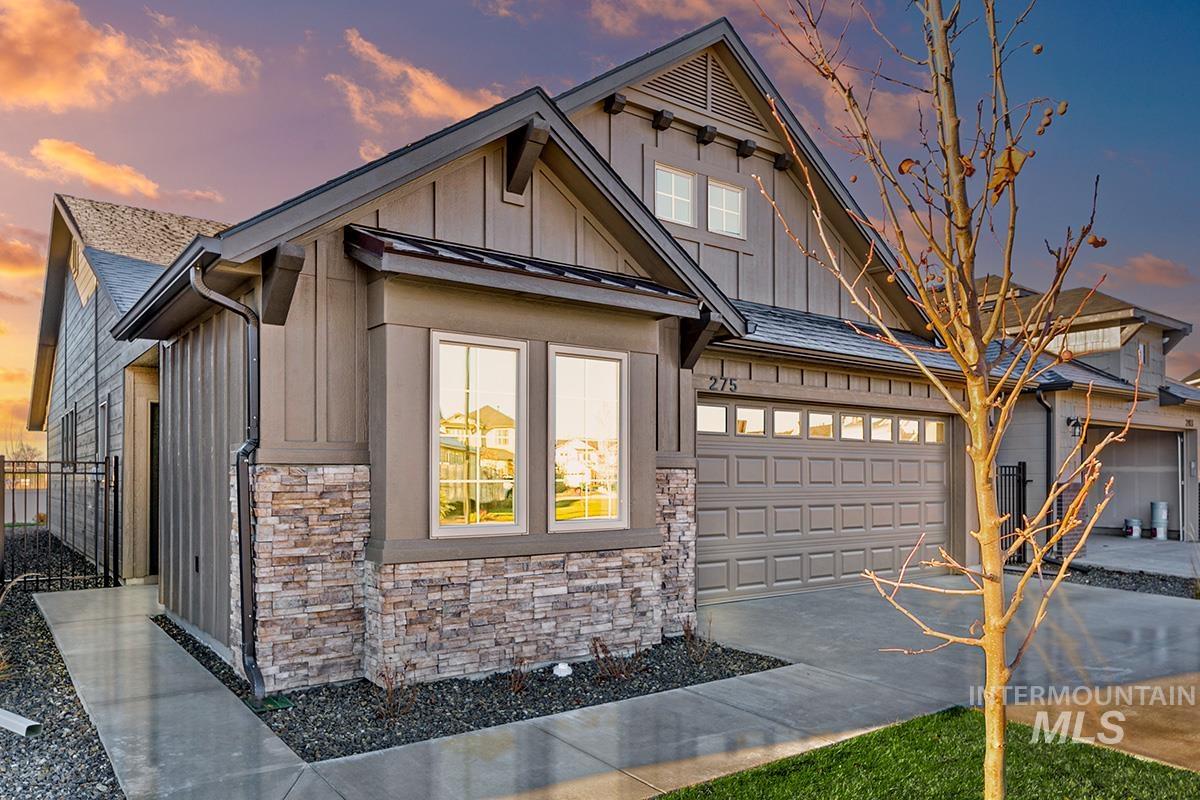 View of front of house with stone siding, board and batten siding, concrete driveway, a garage, and a standing seam roof