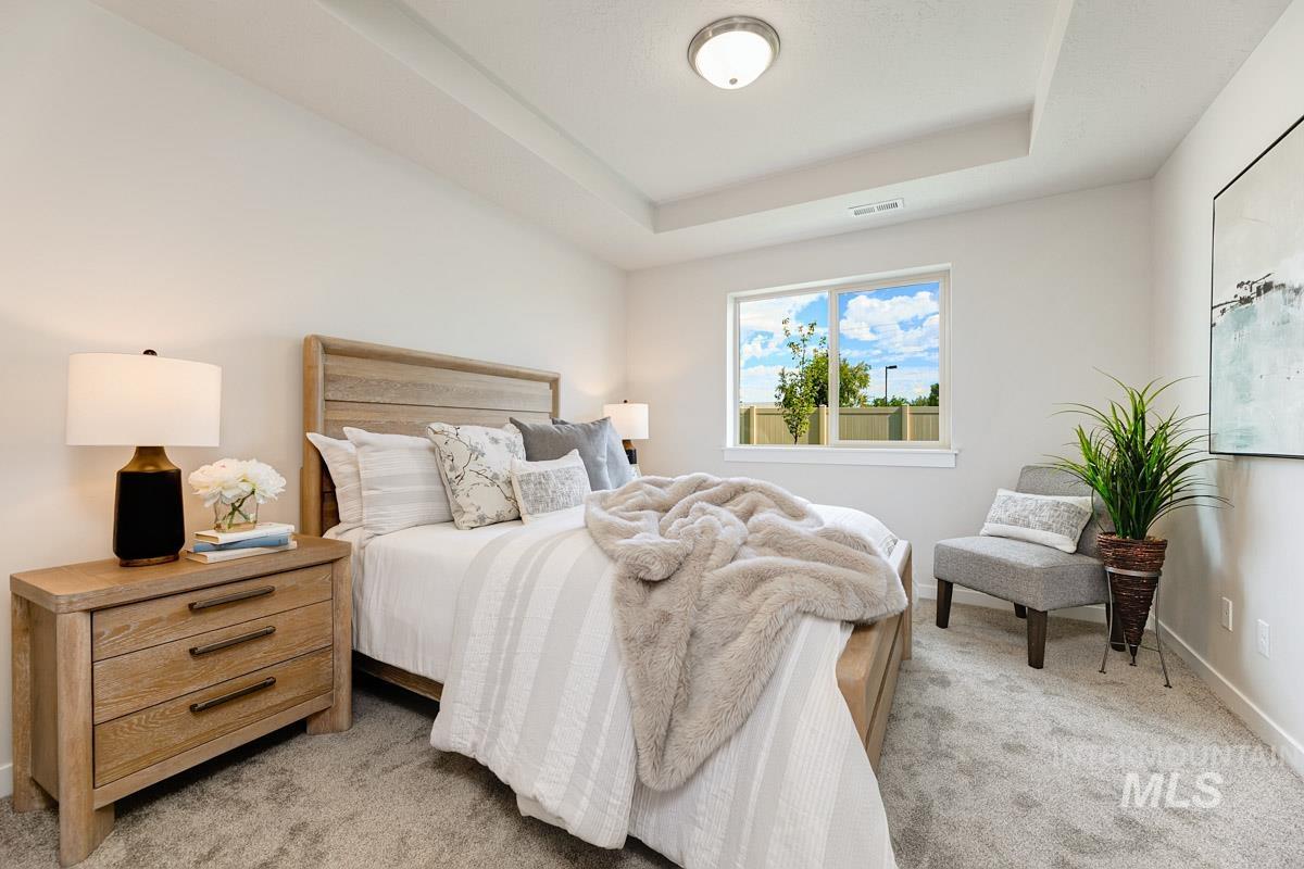 Bedroom featuring a raised ceiling and light carpet