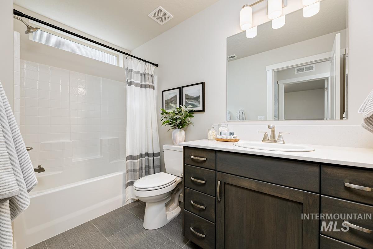 Bathroom with shower / bath combo, vanity, and dark tile patterned flooring
