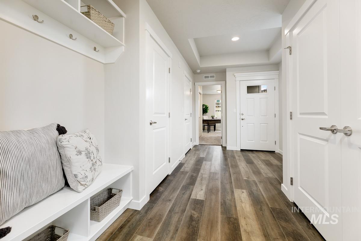 Mudroom featuring dark wood-style flooring, a raised ceiling, and recessed lighting