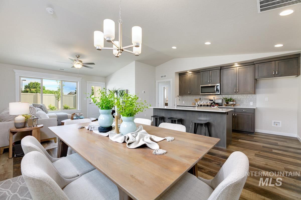 Dining room with lofted ceiling, a chandelier, ceiling fan, dark wood-style floors, and recessed lighting