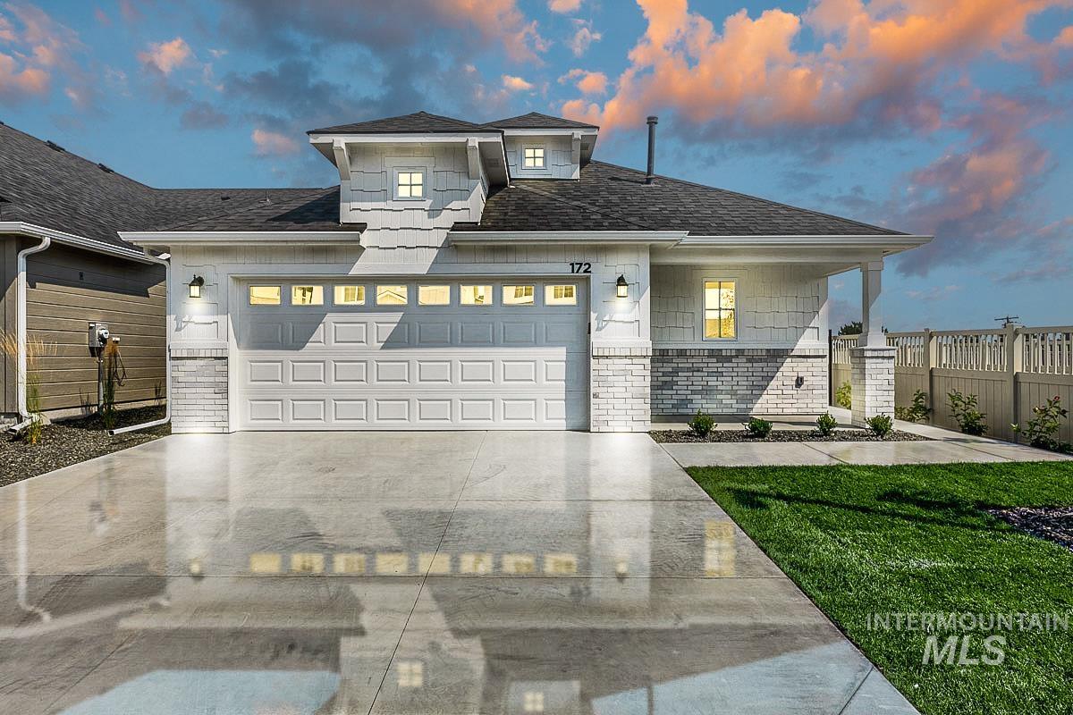 View of front of property featuring brick siding, concrete driveway, a shingled roof, and a garage