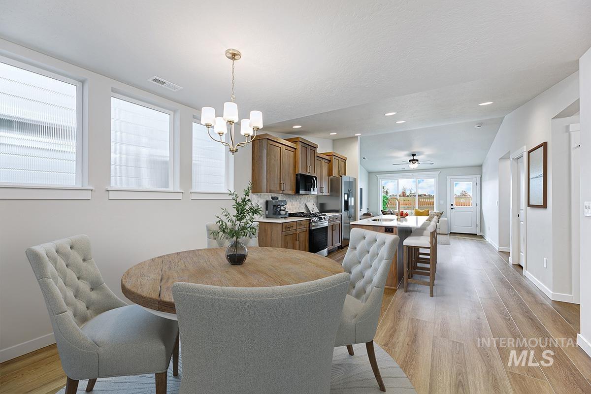 Dining room featuring light wood-type flooring, a ceiling fan, a chandelier, recessed lighting, and vaulted ceiling