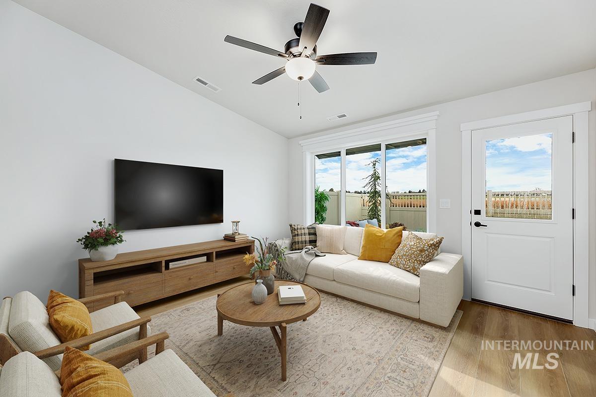 Living area with wood finished floors, vaulted ceiling, and ceiling fan
