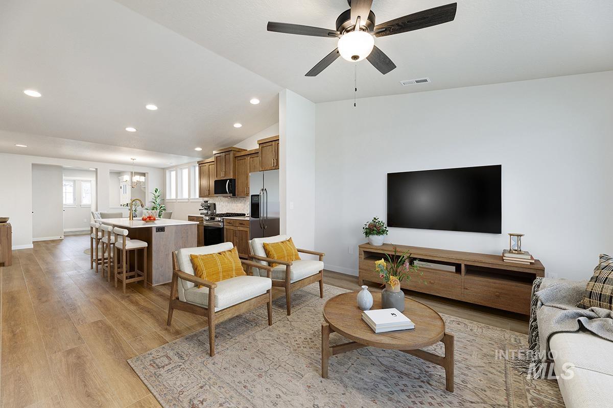 Living room featuring lofted ceiling, recessed lighting, light wood-type flooring, a ceiling fan, and a chandelier