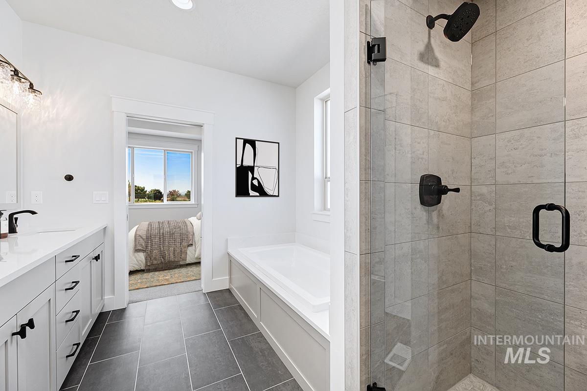 Ensuite bathroom with a stall shower, double vanity, a garden tub, and dark tile patterned flooring