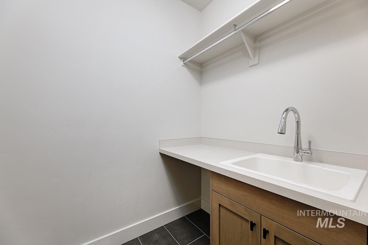 Laundry area with a sink and dark tile patterned floors