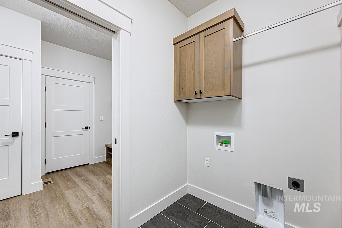 Laundry area with hookup for a washing machine, electric dryer hookup, cabinet space, dark wood-style floors, and a textured ceiling