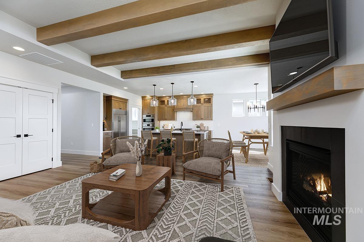Living room featuring recessed lighting, a glass covered fireplace, light wood-style flooring, beam ceiling, and a chandelier