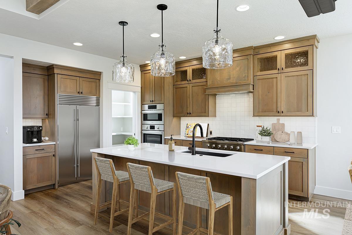 Kitchen featuring decorative backsplash, decorative light fixtures, appliances with stainless steel finishes, a breakfast bar area, and recessed lighting