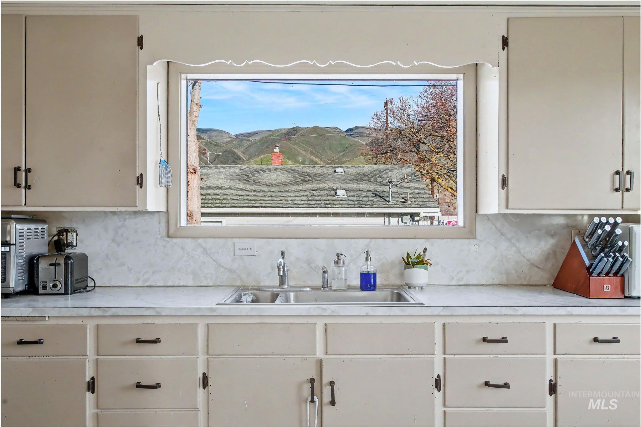 Kitchen featuring light countertops, backsplash, and white cabinetry