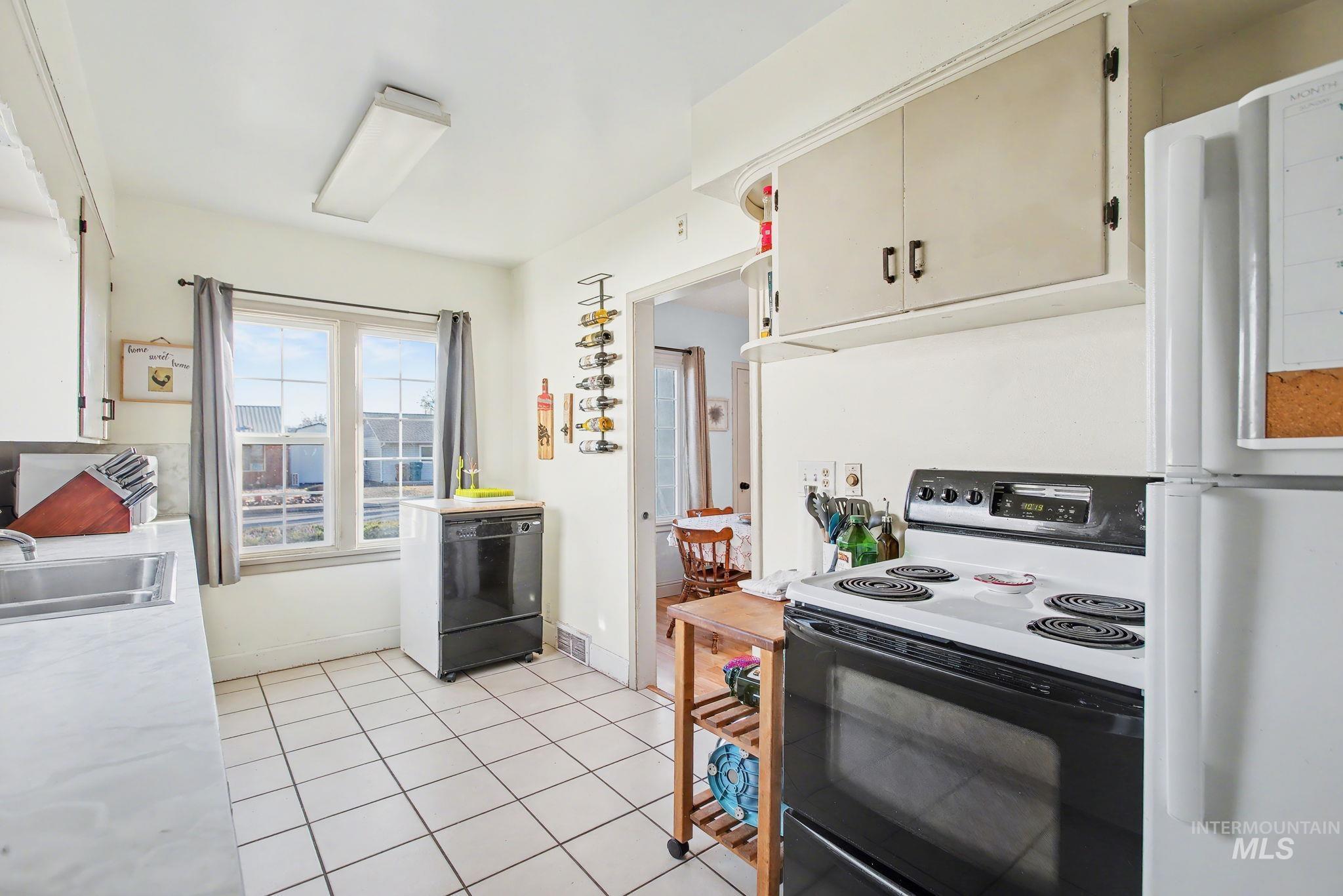 Kitchen with black appliances, light countertops, and light tile patterned floors