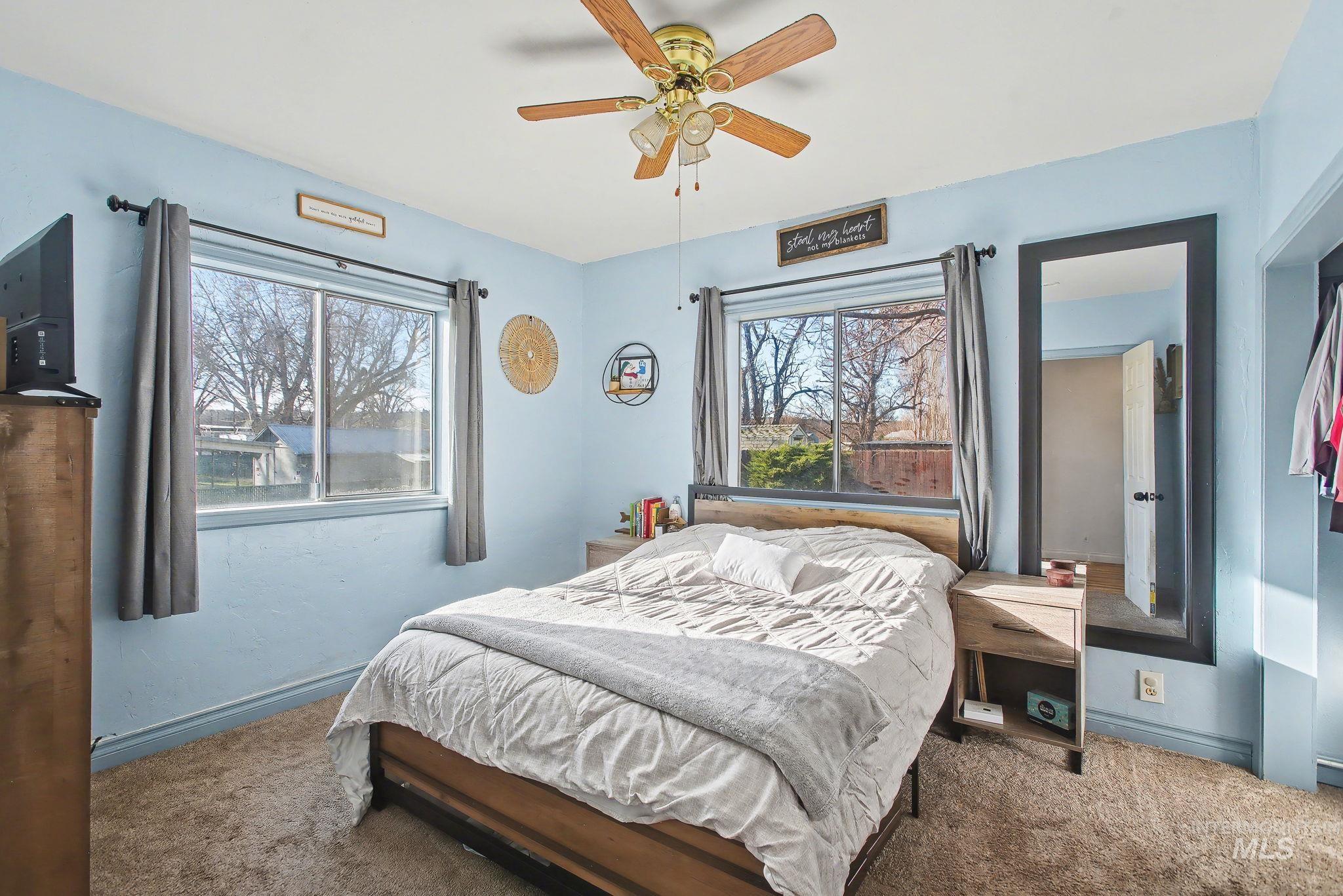 Carpeted bedroom with ceiling fan and baseboards