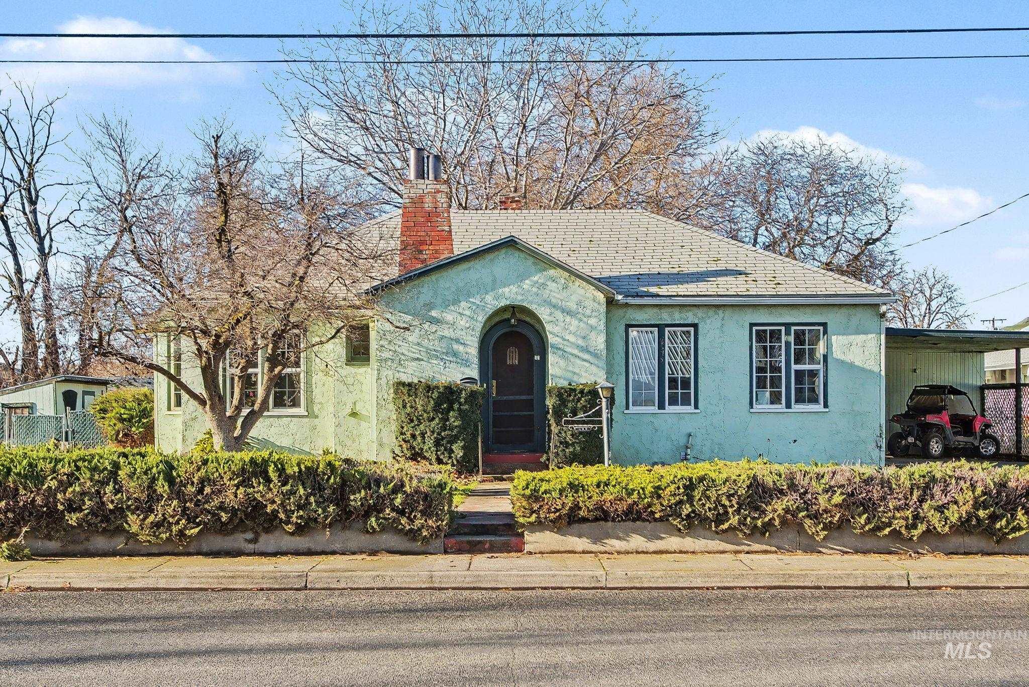 View of front facade with stucco siding, a chimney, and an attached carport