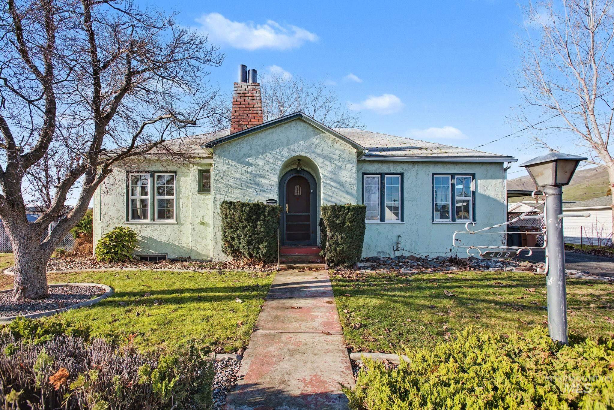 View of front of home featuring stucco siding, a front lawn, and a chimney