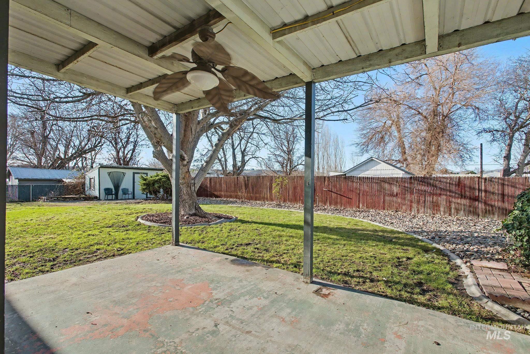 Fenced backyard featuring a ceiling fan, an outbuilding, and a patio area