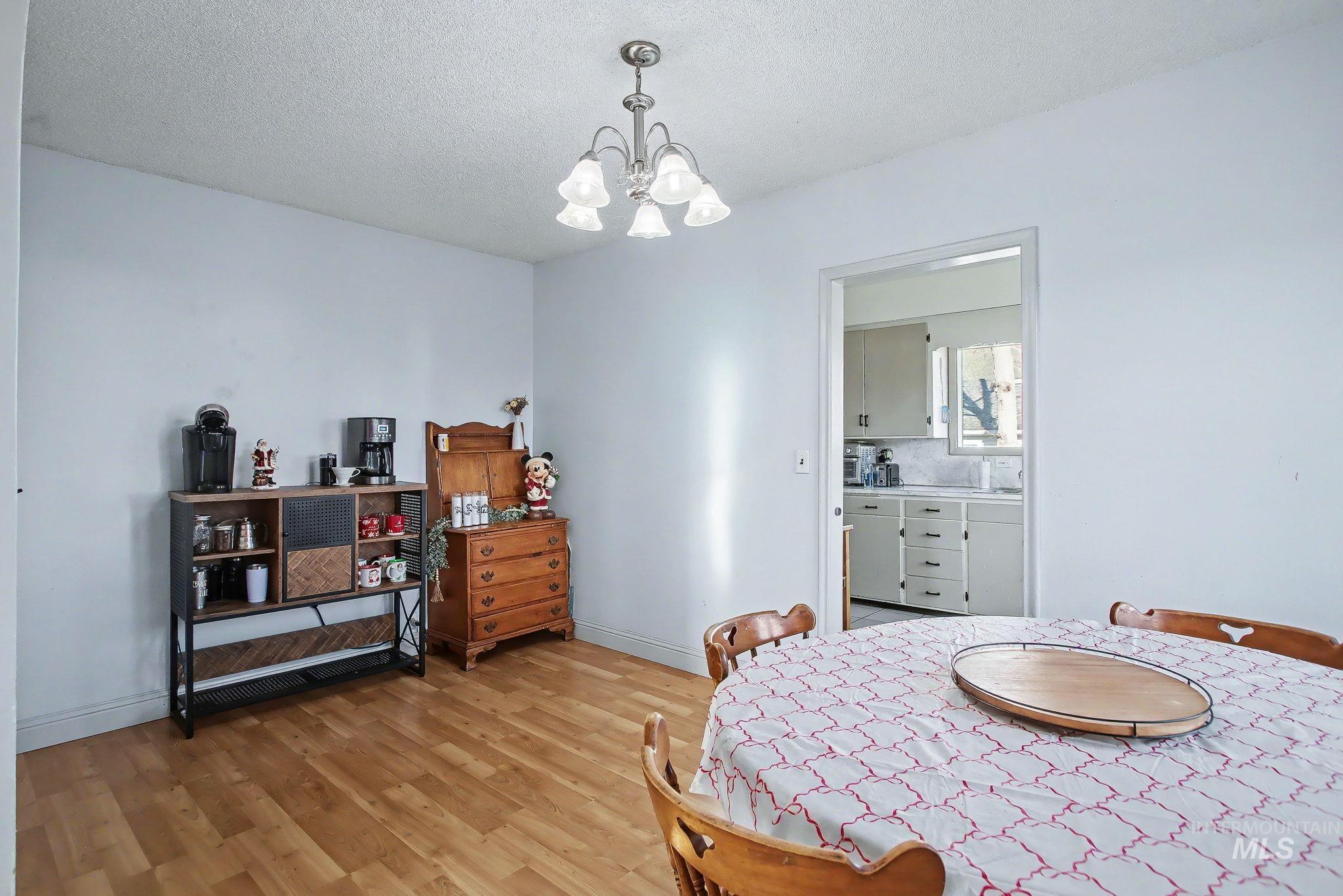Dining space featuring a textured ceiling, light wood-style flooring, and a chandelier