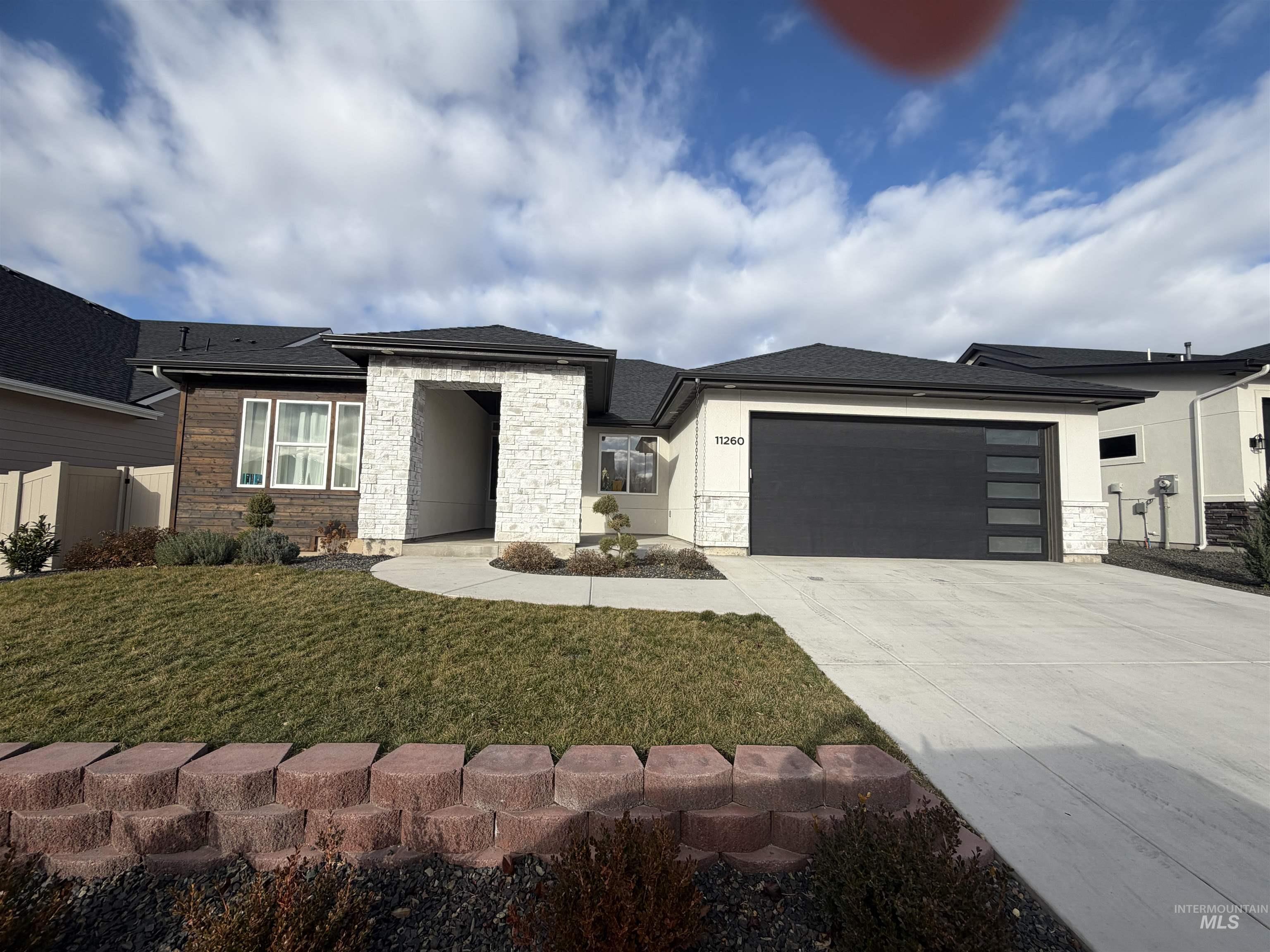 Prairie-style house with stone siding, concrete driveway, a garage, and stucco siding