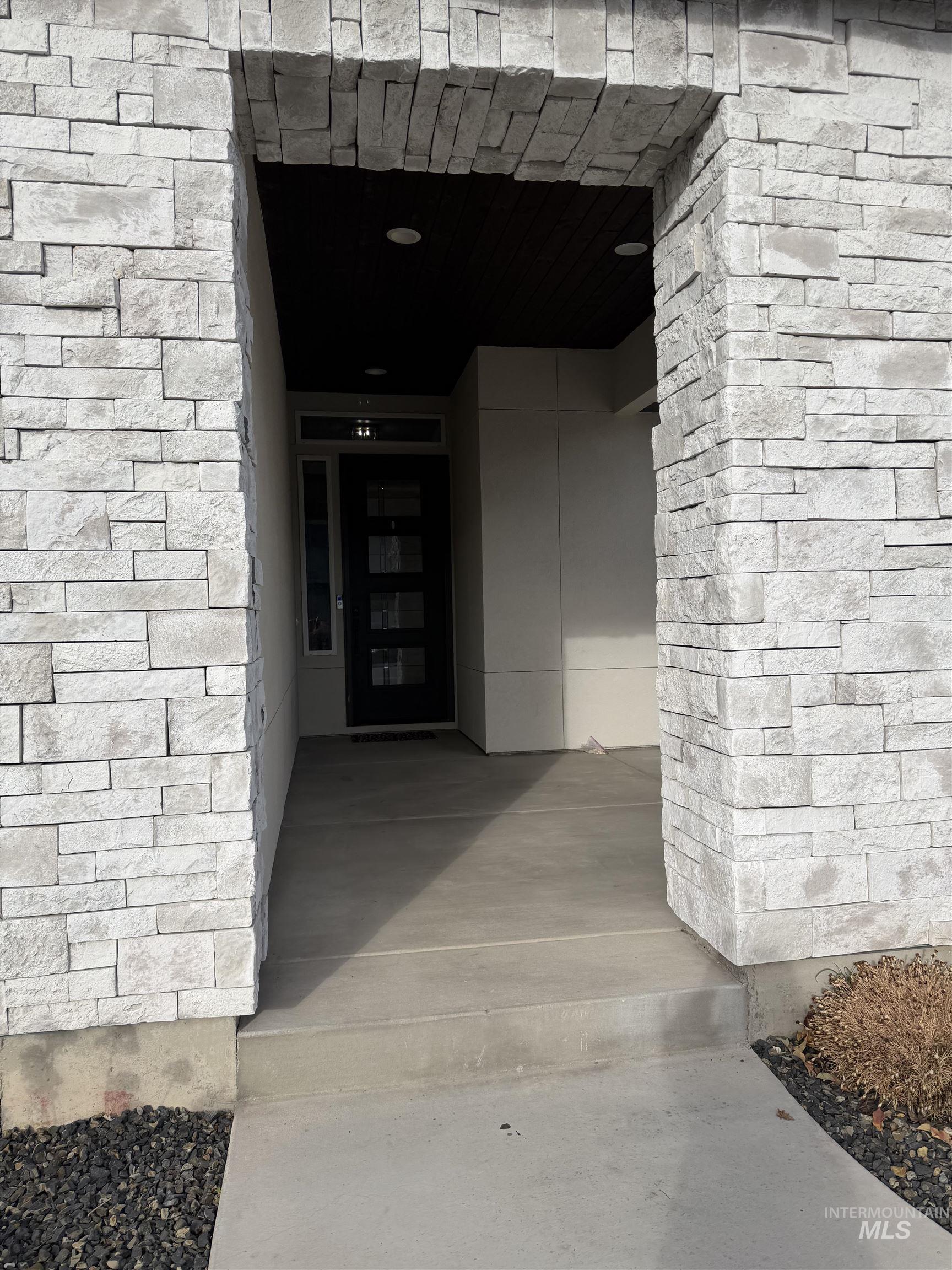 View of exterior entry featuring stone siding and covered porch