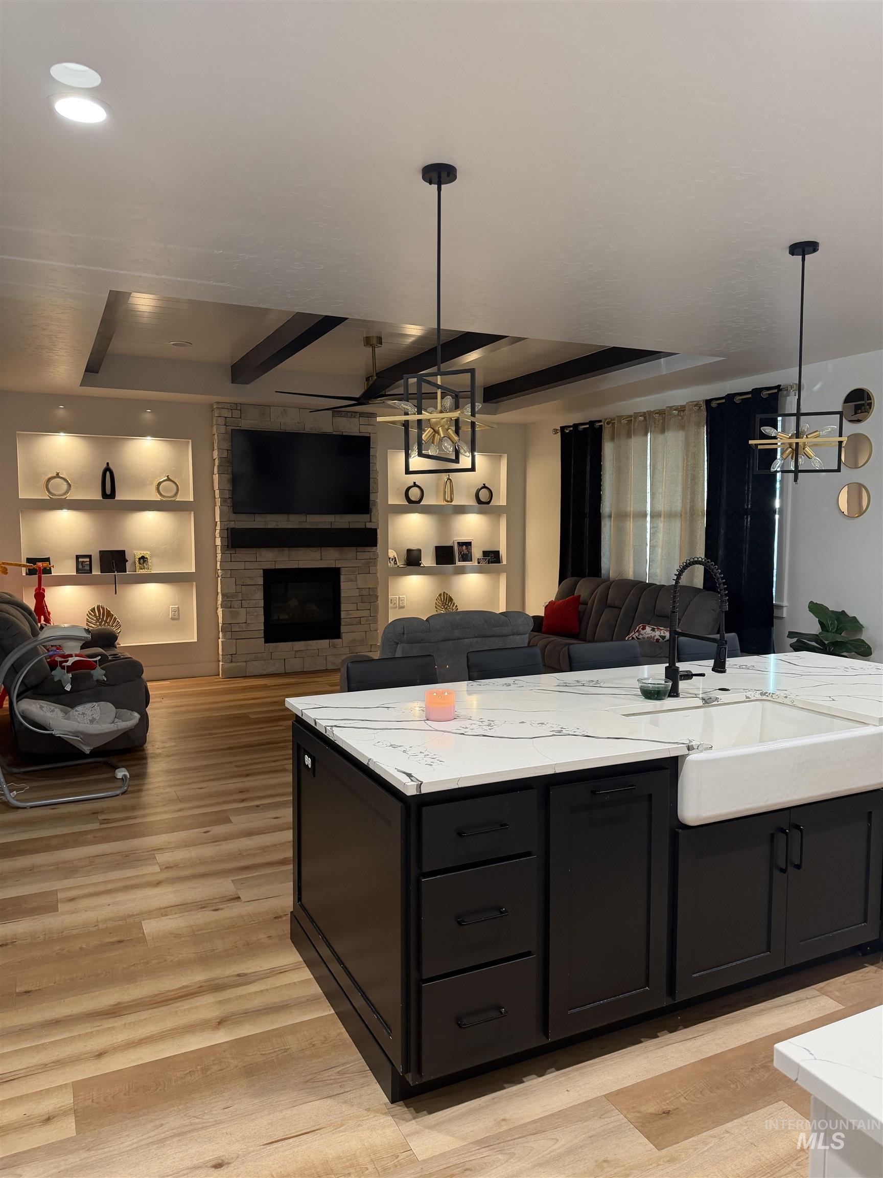 Kitchen featuring dark cabinets, decorative light fixtures, built in shelves, a chandelier, and open floor plan