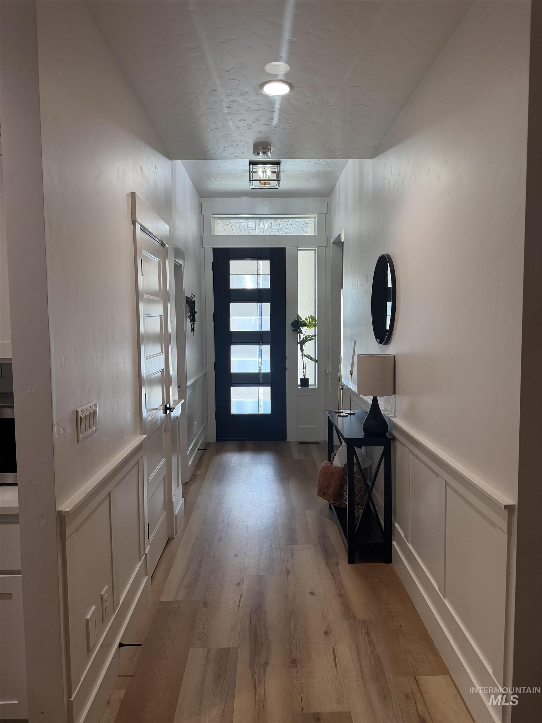 Entryway featuring a decorative wall, wainscoting, and light wood-type flooring