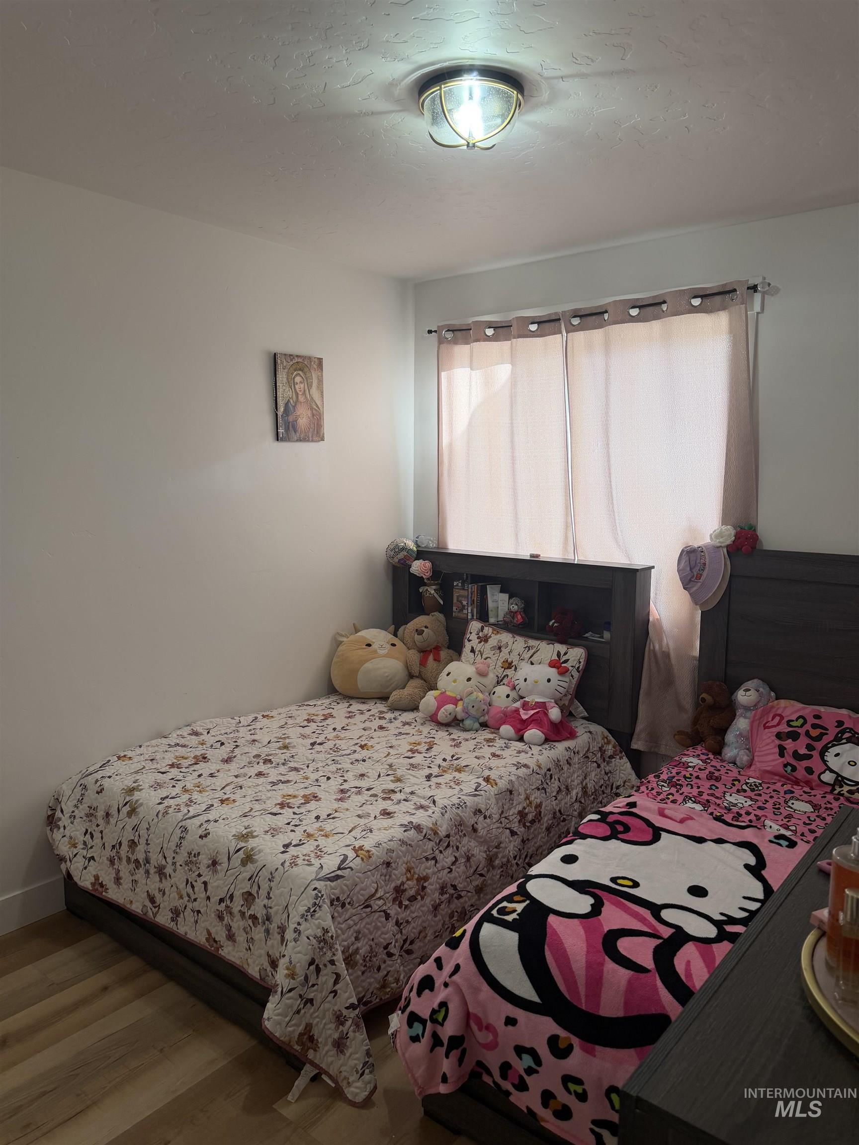 Bedroom with wood finished floors and a textured ceiling