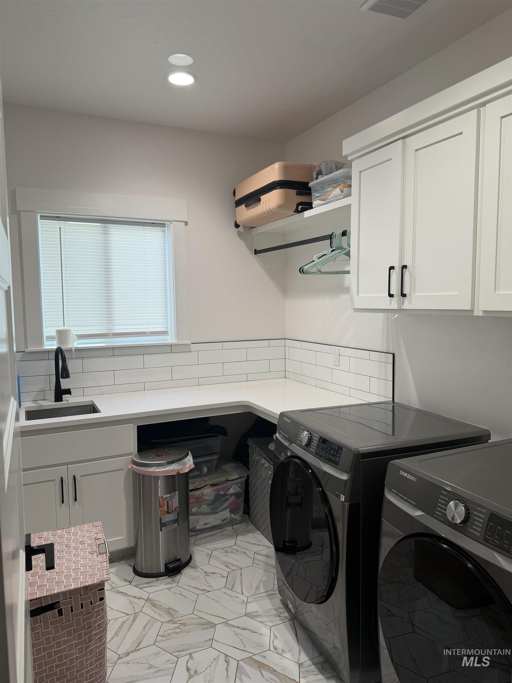 Laundry room featuring cabinet space, separate washer and dryer, light marble finish flooring, and recessed lighting