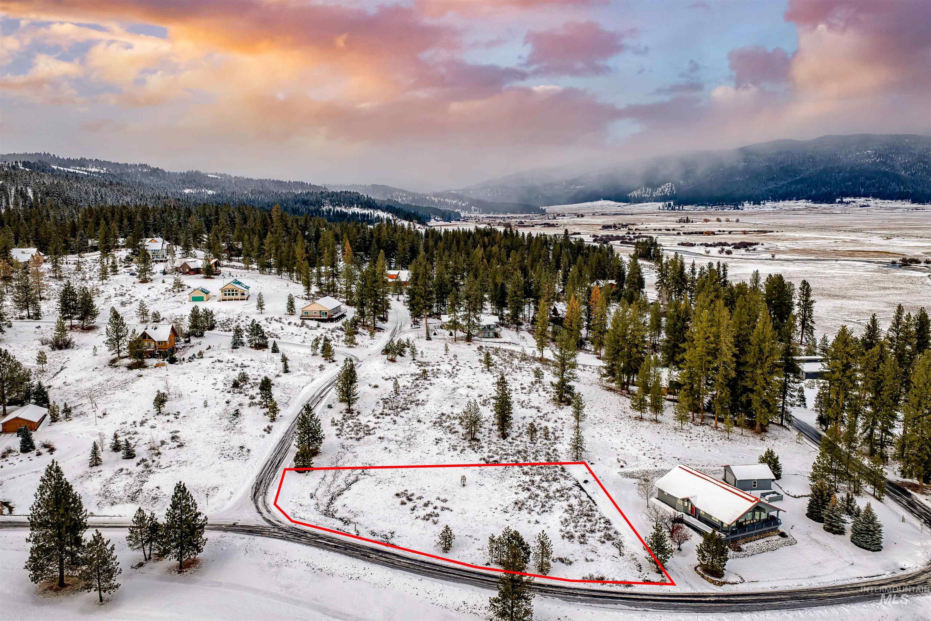 Snowy aerial view featuring property boundaries highlighted and a wooded view