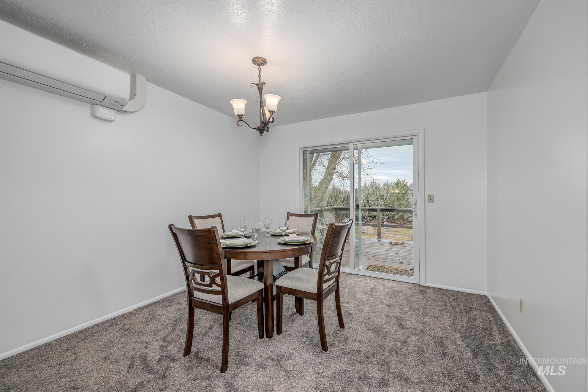 Dining room with a wall mounted air conditioner, carpet, and a chandelier