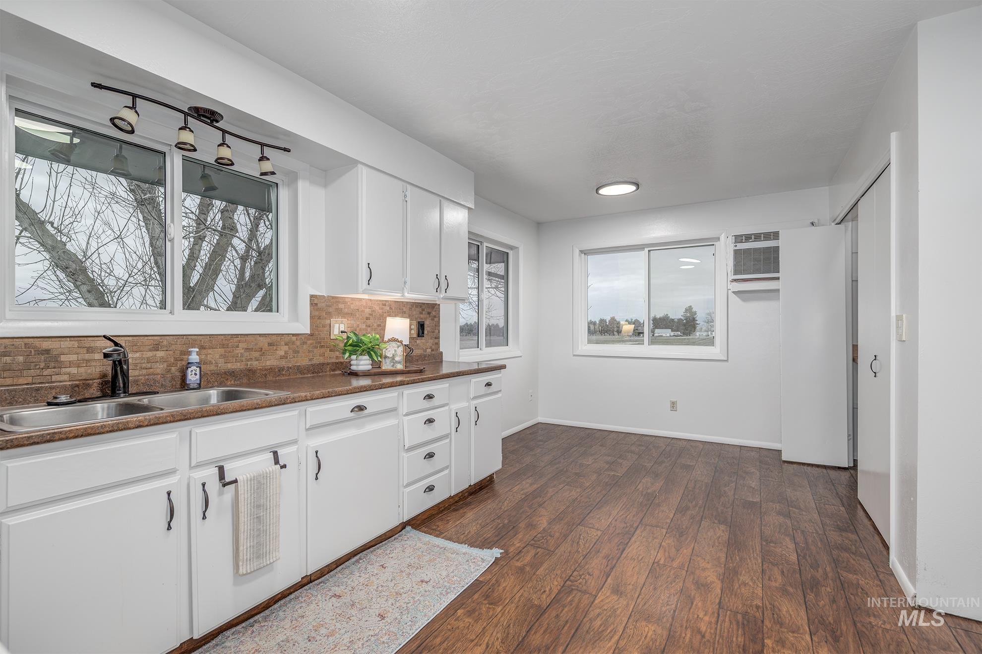 Kitchen with white cabinetry, dark wood finished floors, tasteful backsplash, and a wall mounted AC